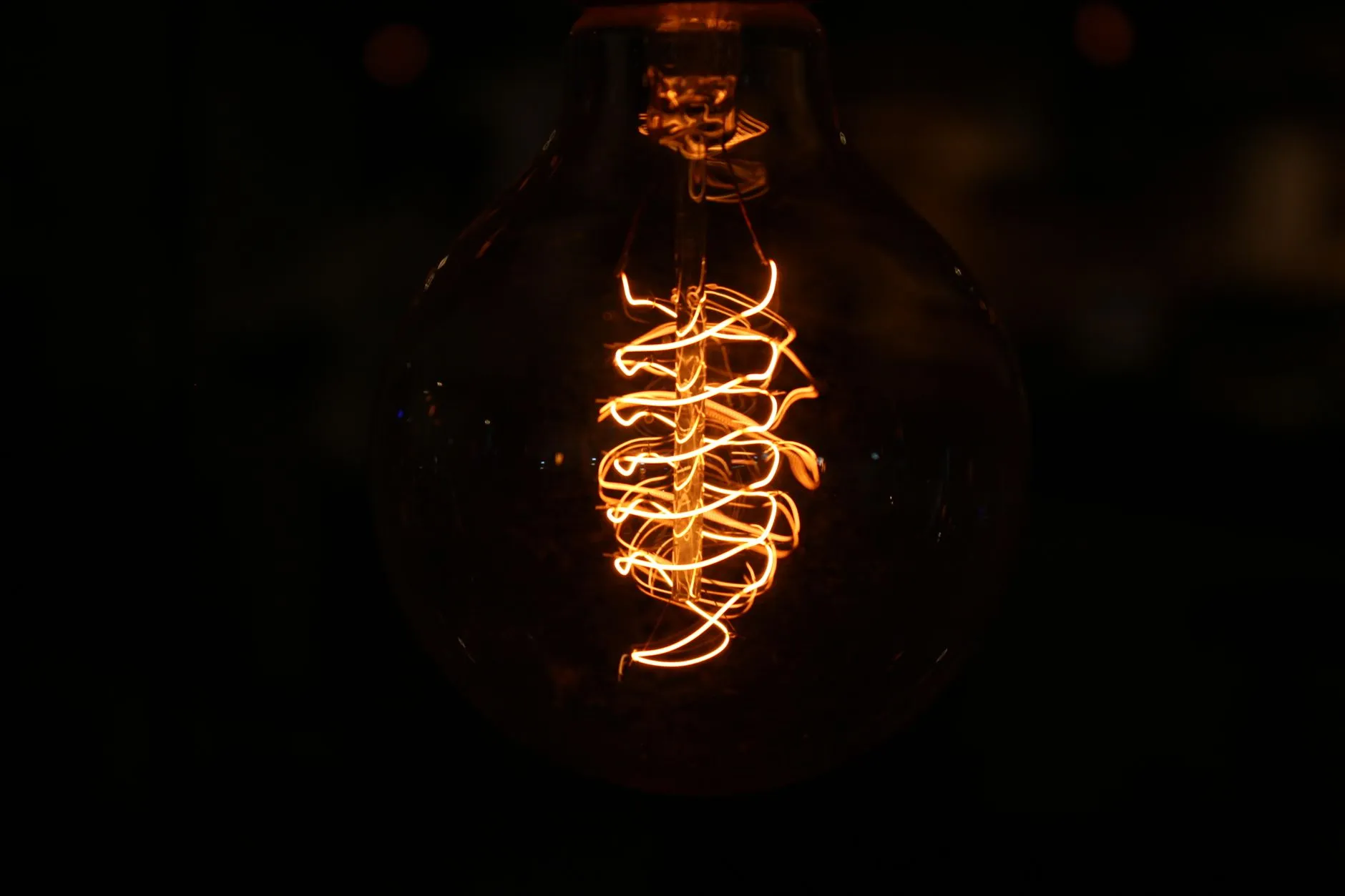 A glowing filament inside a light bulb against a black background